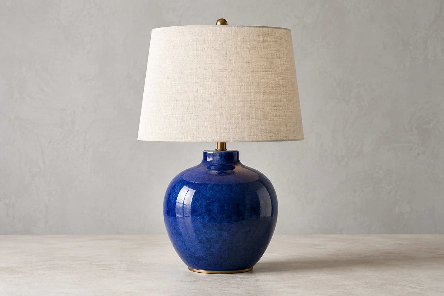Cobalt-blue ceramic table lamp with an ivory shade in a minimal studio